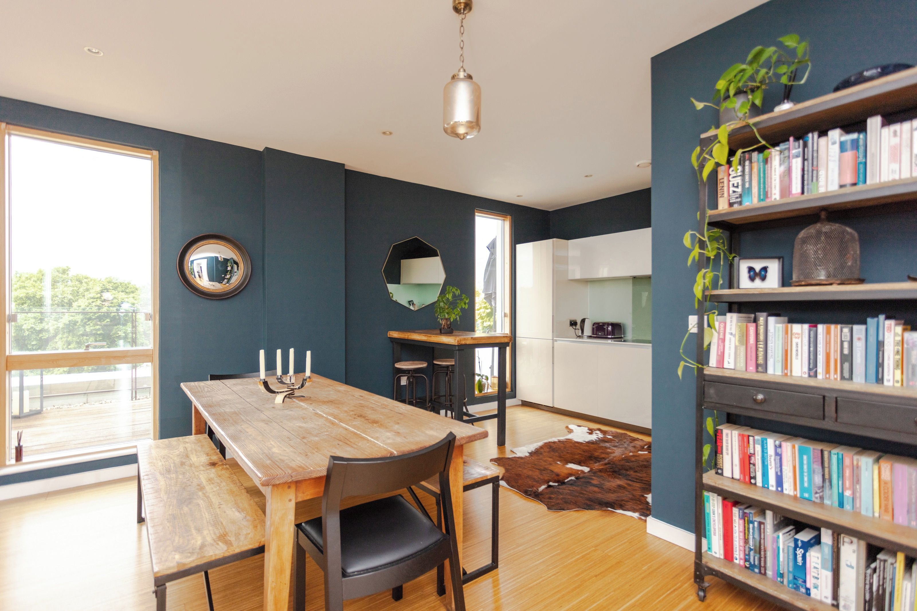 Une cuisine moderne avec une table à manger en bois, une bibliothèque et un grand miroir.