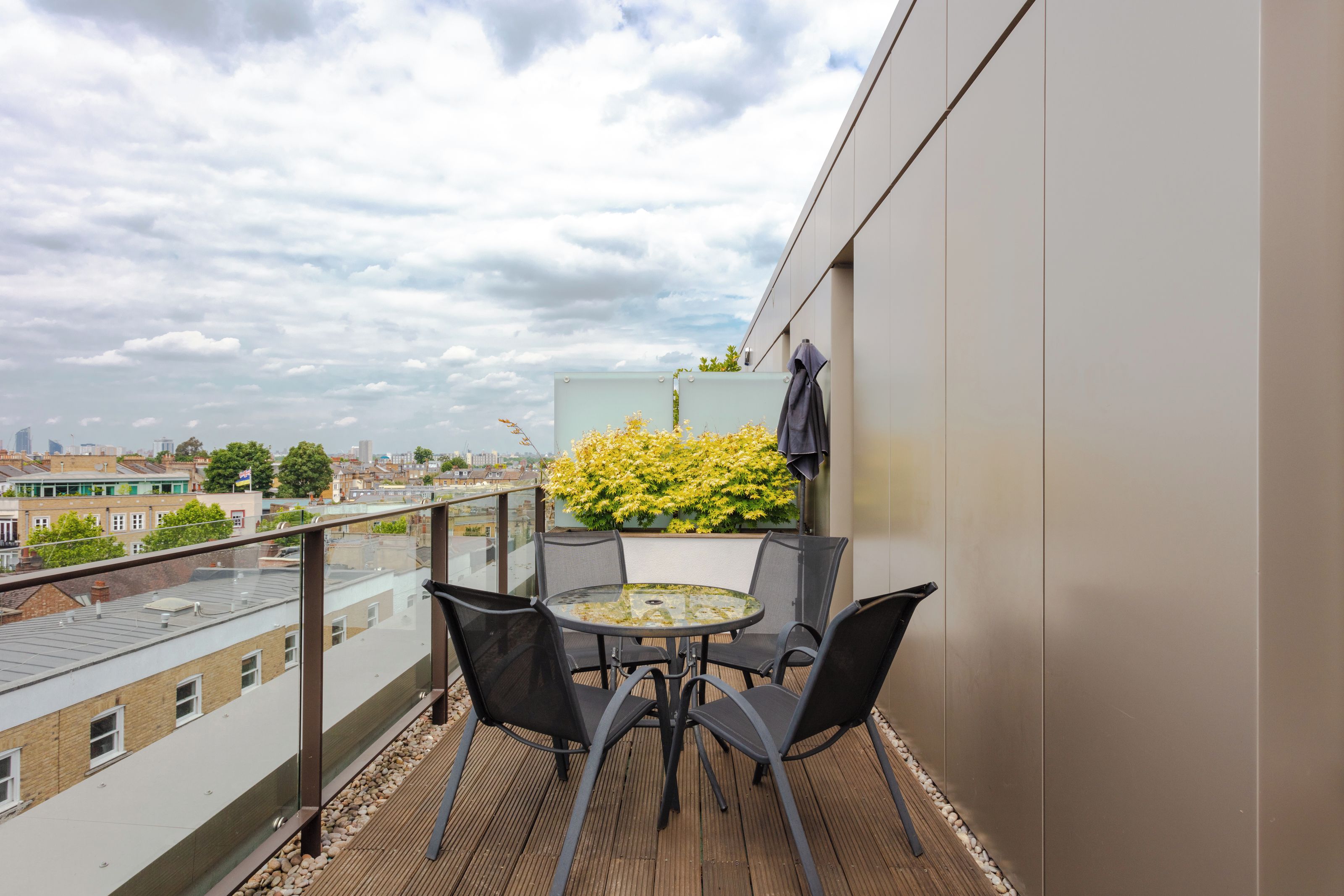 Un balcon avec une table et des chaises, une plante en pot et une vue sur la ville.
