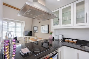 A modern kitchen with a black countertop, white cabinets, and a stainless steel range hood.