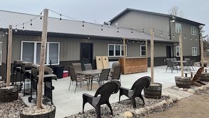 An outdoor patio area with a table and chairs, a grill, and string lights. - Rustic hunt club lodge in the heart of Minnesota lakes country... (Ashby)