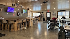 A spacious restaurant with a bar area, high ceiling, and large windows. - Rustic hunt club lodge in the heart of Minnesota lakes country... (Ashby)