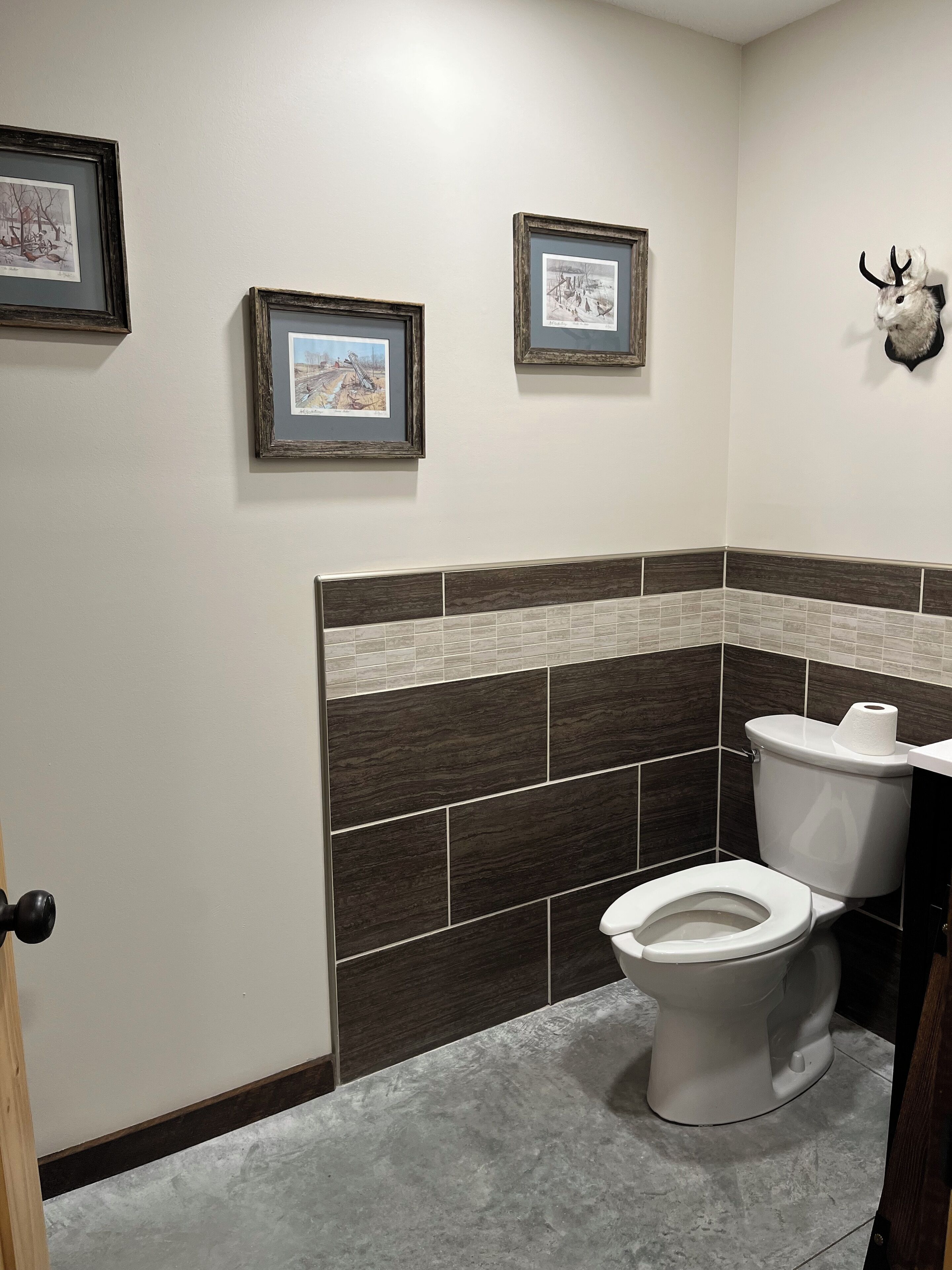 Een badkamer met een toilet, een wastafel en fotolijstjes aan de muur.