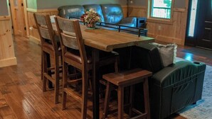 Un coin repas avec une table en bois, quatre chaises et un canapé noir.
