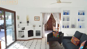 A living room with a black sofa, a coffee table, and a fireplace. There is a staircase leading to an upper floor. - Villa Magica 7 min walking to center, pool & A/C (Playa Blanca)