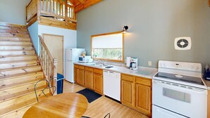 Une cuisine avec des meubles de rangement en bois, une cuisinière, un four à micro-ondes et un évier.