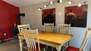 Ruokailutilassa on puinen pöytä ja neljä tuolia, joissa kaikissa on punainen istuintyyny. Pöydän yläpuolella on kaksi seinään kiinnitettyä valaisinta.