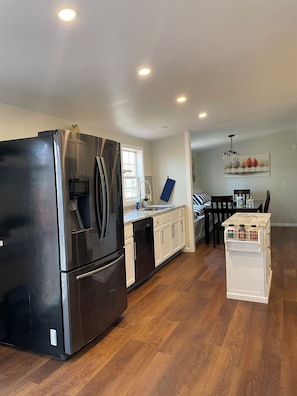 Una cocina moderna con electrodomésticos de acero inoxidable, una encimera blanca y piso de madera.