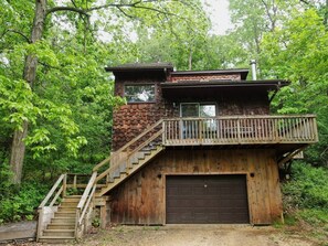 Un chalet rustique avec une façade en bois, un balcon et un garage.