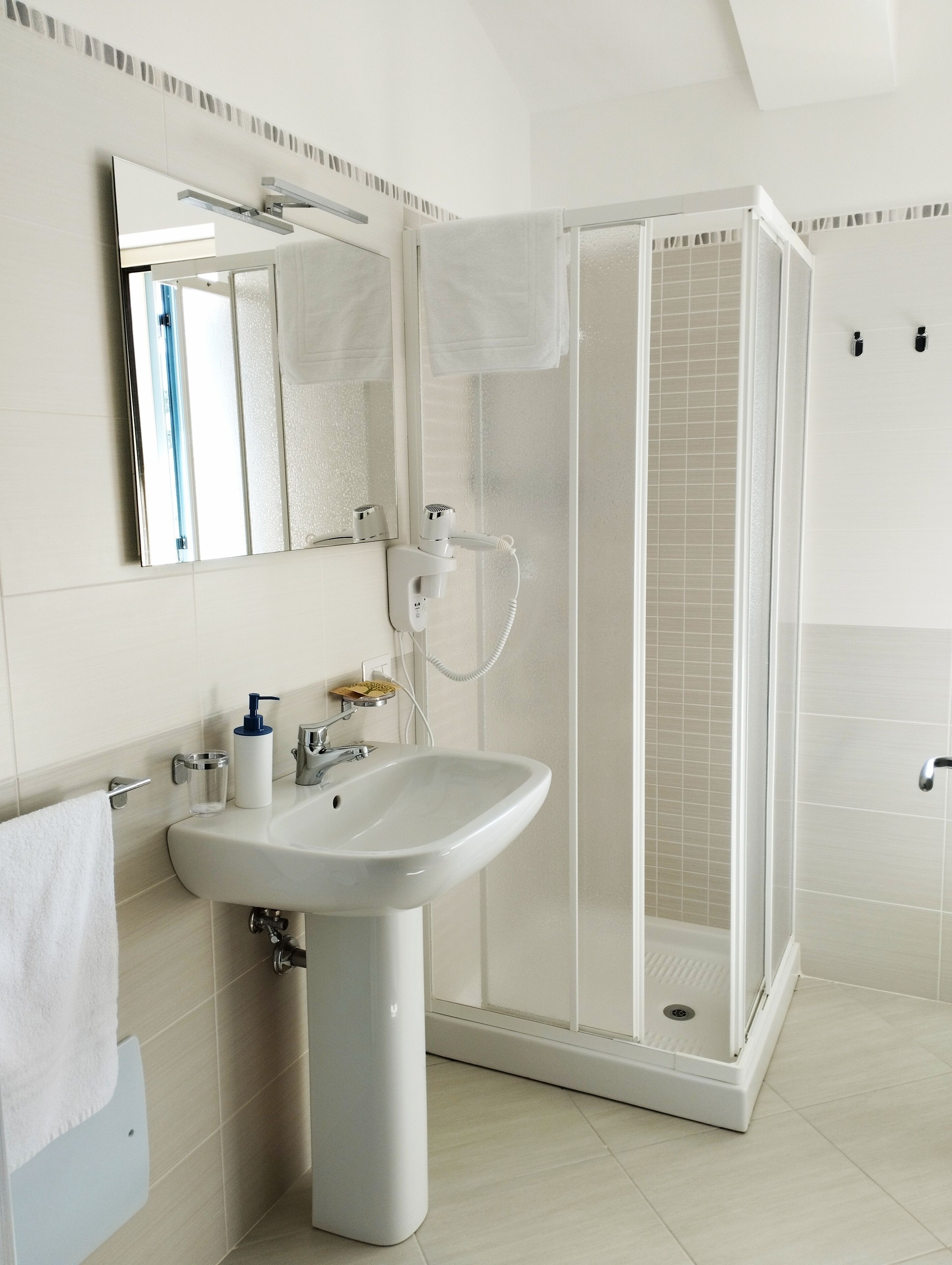 Ein modernes Badezimmer mit Waschbecken, Spiegel und Duschkabine.