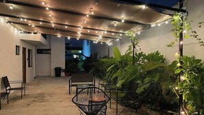 An outdoor patio area with string lights, chairs, and potted plants.