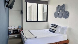 Ein Schlafzimmer mit Bett, Fenster, einem an der Wand befestigten Fernseher und einem Wanddekor.