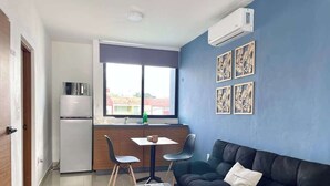 Ein kompakter Wohnraum mit Küchenzeile, Essbereich, einer Couch und einem Fenster mit Blick.