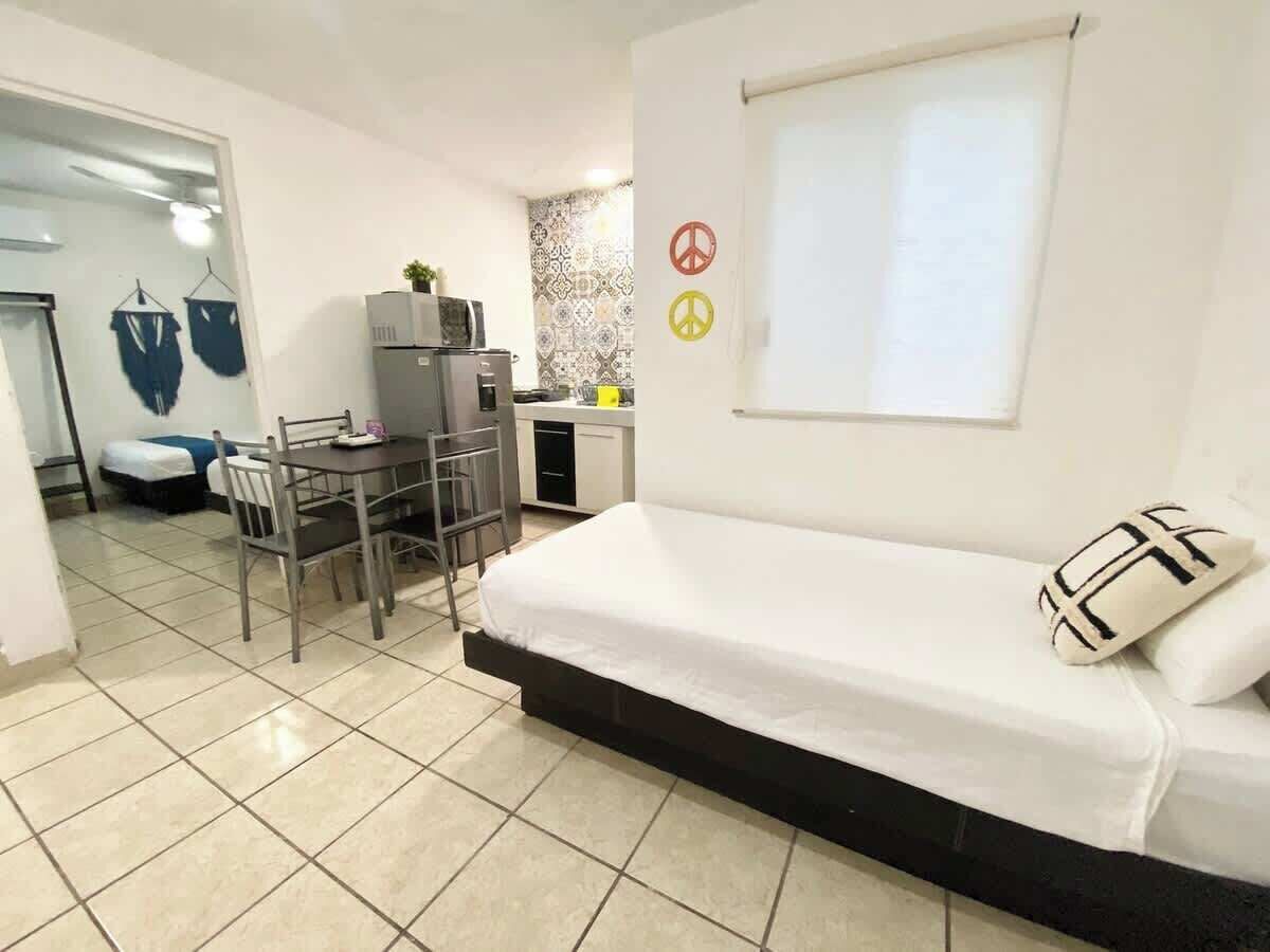 Een kleine kamer met een bed, een bureau en een stoel. Er is een raam met uitzicht op de omgeving.