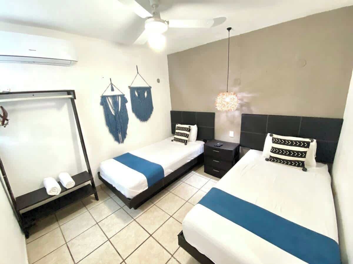 Een hotelkamer met twee bedden, een garderobe, een plafondventilator en een hanglamp.