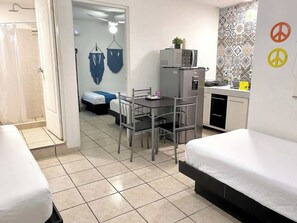A compact room with a bed, a small table, and a kitchenette.