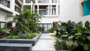 Un bâtiment moderne doté d’une cour intérieure agrémentée de diverses plantes et d’un chemin en marbre.