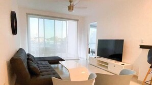 A modern living room with a sofa, TV, and two chairs. - 3BR Apartment | 3 Ensuites | Pool | Near Beach (Playa del Carmen)