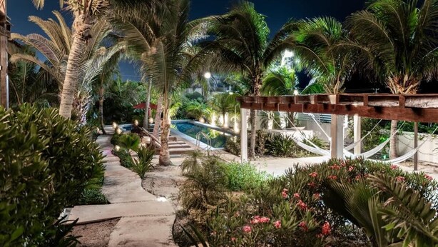 A pathway leading to a pool area with palm trees and a hammock. - Isla Mujeres Villa | Plunge Pool, Beach 90m & A/C (Isla Mujeres)