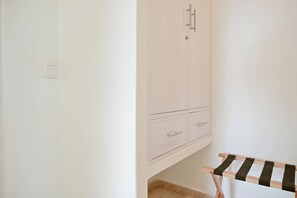 Una habitación con un armario blanco, una mesita con mantel a rayas y un interruptor de luz en la pared.