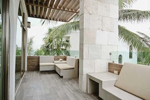 A modern outdoor seating area with a pergola, stone walls, and tropical plants.