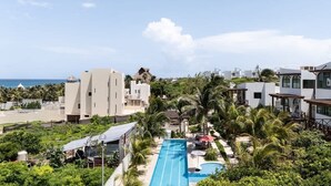 A resort with a swimming pool, palm trees, and modern buildings. - Isla Mujeres Villa | Plunge Pool, Beach 90m & A/C (Isla Mujeres)