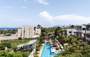 Un resort con piscina, palmeras y vistas al océano.