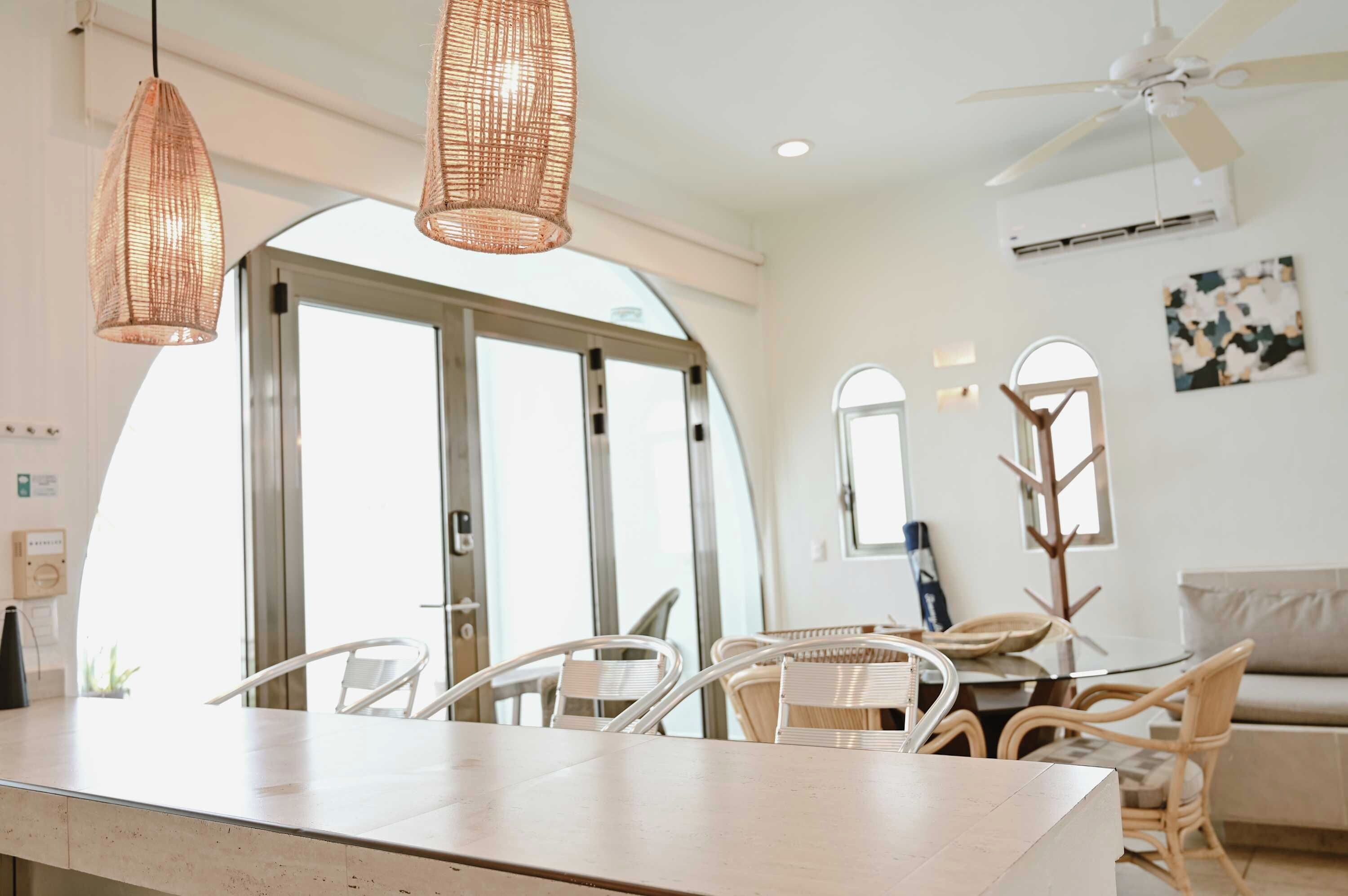 A dining area with wicker chairs, a white table, and a ceiling fan.