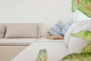 En modulopbygget sofa med stof i neutrale farver, ledsaget af to puder, en ensfarvet og en stribet.