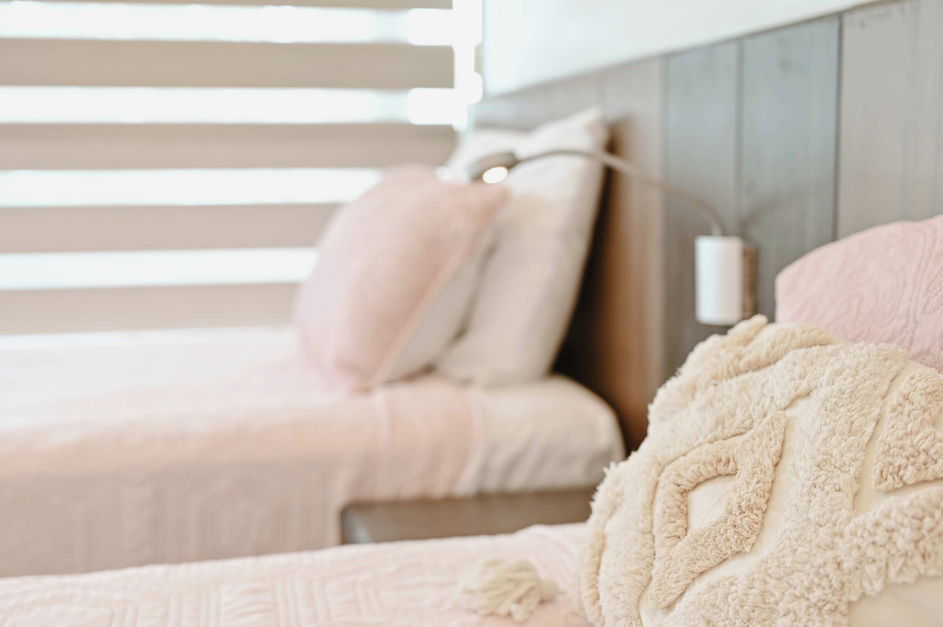 A bedroom with two beds, each with a pillow and a blanket.