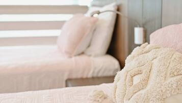 A bedroom with two beds, each with a pillow and a blanket.