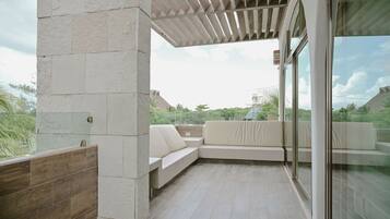 A modern outdoor seating area with a glass partition, a wooden pergola, and a view of the surrounding landscape.