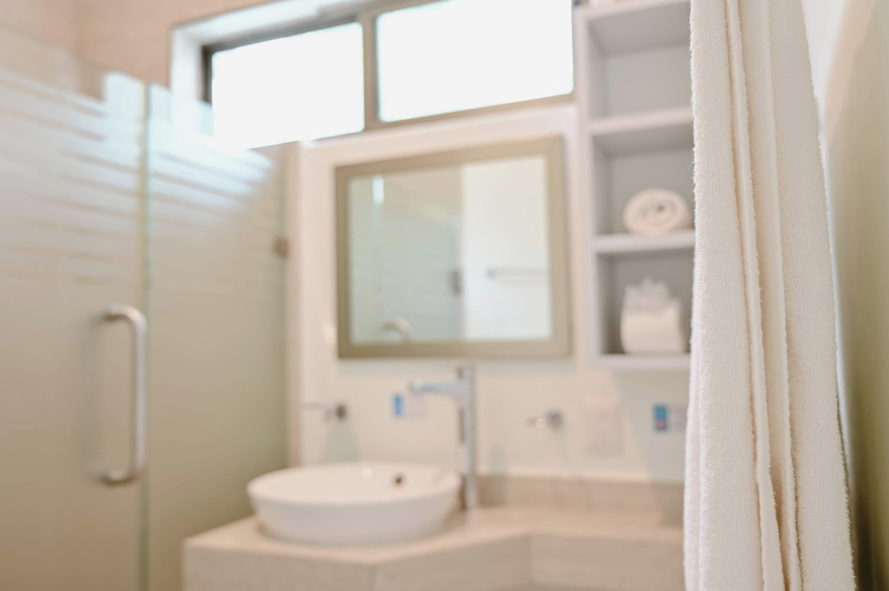 A bathroom with a white sink, a mirror above it, and a towel rack to the right.