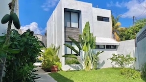 A modern two-story building with a flat roof, large windows, and a small balcony. - Downtown Cancun King Suite | Garden, WiFi & AC (CancÃºn)