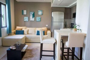 Un salon moderne comprenant un canapé, une table basse et un coin repas avec des chaises.