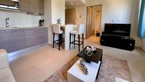 Un salon moderne avec un téléviseur, une table basse et deux tabourets de bar.