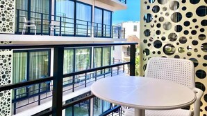 Ein modernes Gebäude mit Balkon, großen Fenstern und einem runden Tisch.