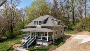 A two-story house with a covered porch and a staircase leading to the upper level.