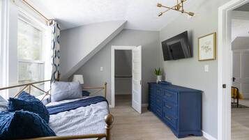 Ein Schlafzimmer mit einem Bett, einem Schminktisch, einem Fernseher und einer Treppe zu einer oberen Ebene.
