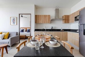 Eine moderne Küche mit Holzausstattung, einer schwarzen Arbeitsplatte und einem Essbereich mit Tisch für vier Personen.