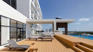 Eine Dachterrasse mit Liegestühlen, einem Pool und einem modernen Gebäude mit großen Fenstern.