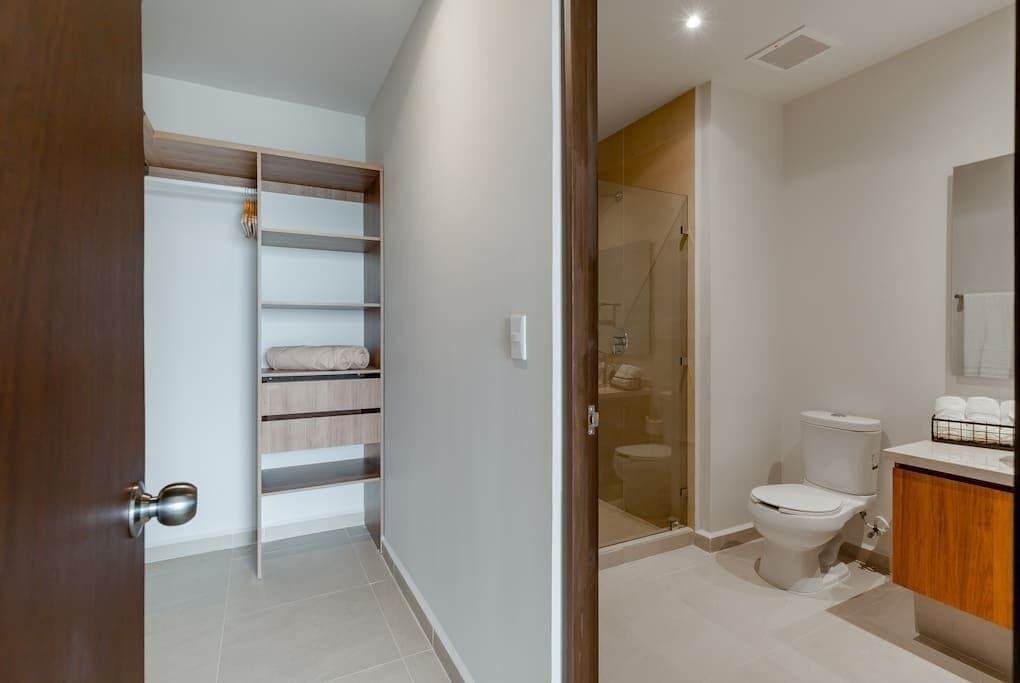 A modern bathroom with a glass shower enclosure, a toilet, and a wooden vanity.