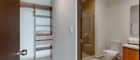 A modern bathroom with a glass shower enclosure, a toilet, and a wooden vanity.