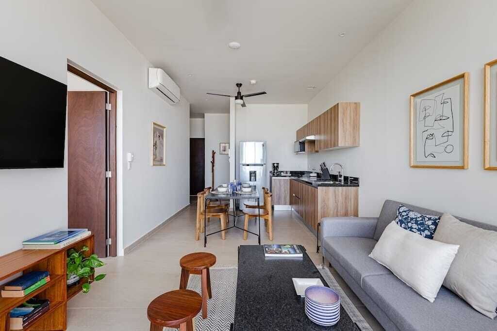 A modern living room with a sofa, coffee table, and a dining area with chairs and a table.