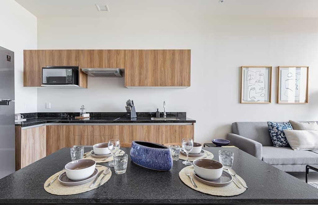 Une cuisine moderne avec des meubles en bois, un four à micro-ondes et un coin repas avec une table dressée pour deux personnes.