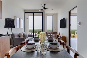 Enjoy meals in this stylish dining area with a long table for four, a central vase, and a flat-screen TV.