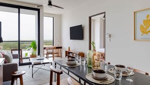 A modern dining area with a long table, chairs, and a view through large windows. - Cancun 1BR | Lagoon View, Pool & Gym | SF 801 (CancÃºn)
