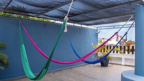 A hammock suspended between blue pillars on a rooftop terrace with a view of the cityscape. - Central Studio + Rooftop, Downtown Cancun (Cancún)