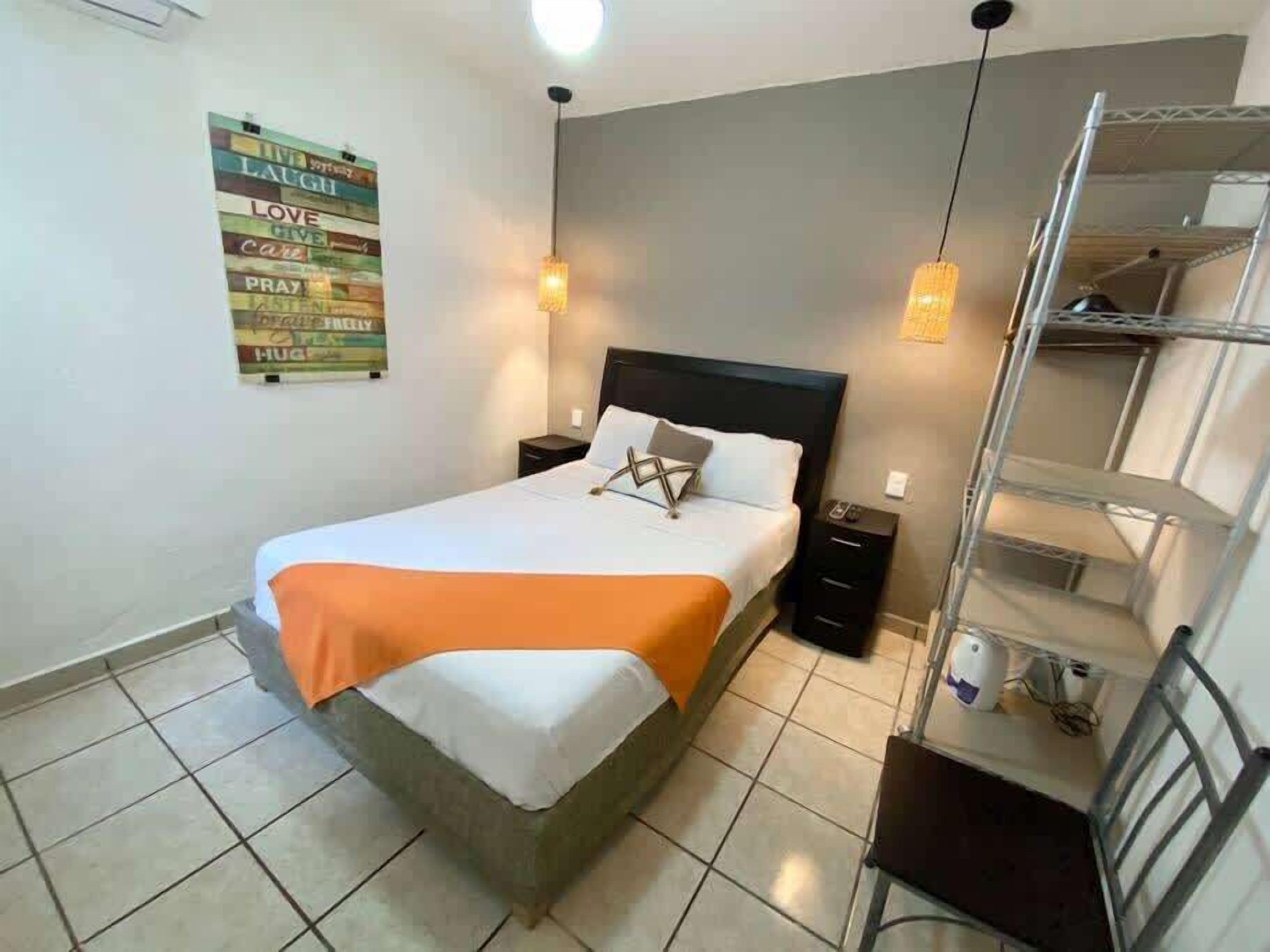 A bedroom with a bed, nightstands, a wall art piece, and a shelving unit.