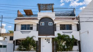 A two-story building with a central entrance, a garage door, and a number '20' on the facade. - Cancun Central Studio: Rooftop Terrace & Kitchen (CancÃºn)