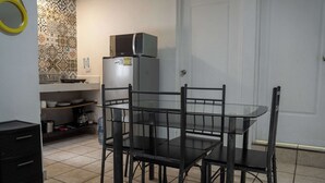A compact kitchen with a dining table and chairs, a refrigerator, and a microwave. - Cancun Central Studio: Rooftop Terrace & Kitchen (CancÃºn)